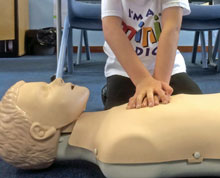 A Mini Medics student practices CPR resuscitation on a dummy Image of a Mini Medics student practicing CPR on a dummy
